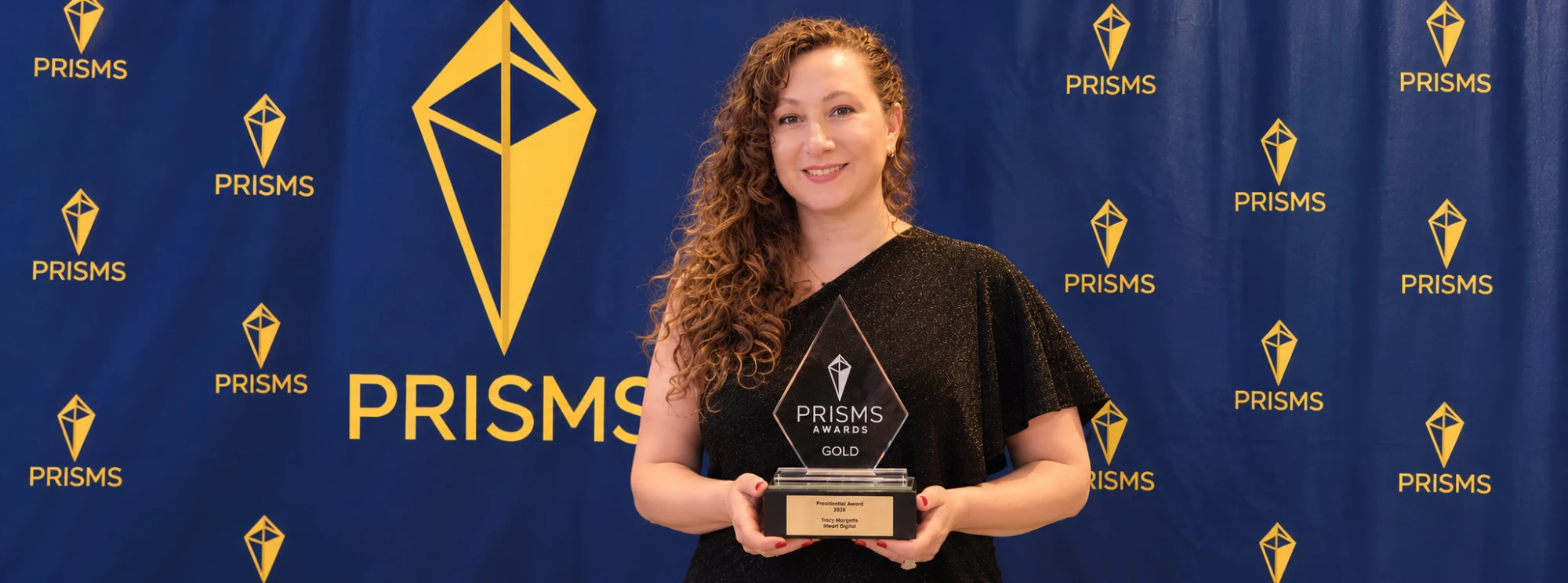 Tracy Margetts, founder of iHeart Digital, holding her Gold PRISMS Presidential Award at the PRISMS 2026 Awards